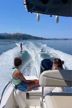 two people are riding on a boat in the water while another person is standing behind them