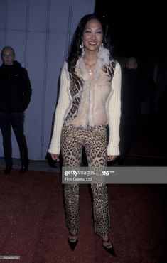 an image of a woman in leopard print pants and fur vest posing for the camera