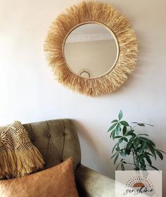 a round mirror hanging on the wall above a chair with pillows and a potted plant