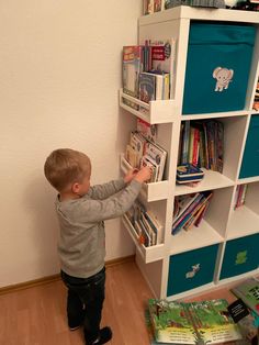 a little boy that is standing in front of a book shelf