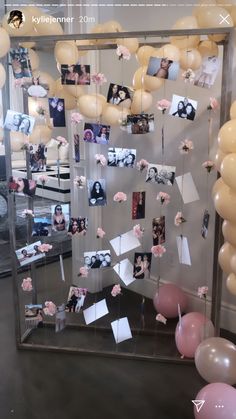 a display case with pictures and balloons on the wall in front of it that has been decorated with pink flowers