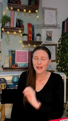 a woman sitting at a desk with her hands in the air while talking to someone