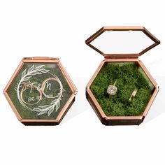 an open box with two wedding rings in it and the inside is filled with moss