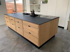 a kitchen with an island made out of wood and black counter tops, in front of a large window