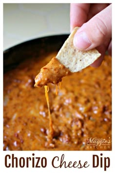 a hand holding a tortilla chip and dipping it into a chili cheese dip