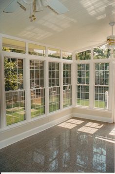 an empty room with large windows and tiled floor