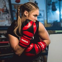 a woman wearing red boxing gloves with her arms wrapped around her chest and looking at the camera