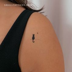 the back of a woman's shoulder with a small cat tattoo on her left arm