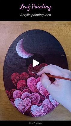 a person is painting hearts on a black and pink plate with a red pencil in their hand