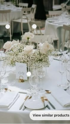 the table is set with white flowers and place settings for guests to sit down at