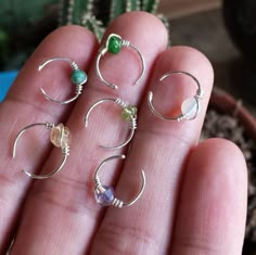 a person is holding five different rings in their hand, all with beads and stones on them