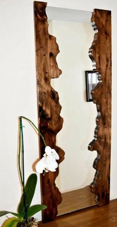 a vase with flowers sitting on top of a wooden table next to a large mirror