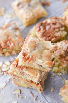 several pieces of dessert sitting on top of a piece of parchment paper with nuts scattered around it