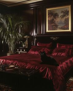 a black cat sitting on top of a red bed in a room with palm trees