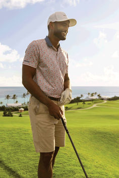 a man standing on top of a lush green field holding a golf racquet