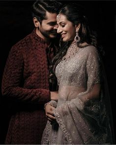 a man and woman standing next to each other in front of a dark background,