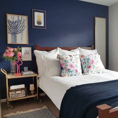 a bedroom with blue walls, white bedding and pink flowers on the headboard