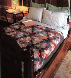 a bed with a quilt on top of it in a bedroom next to a table