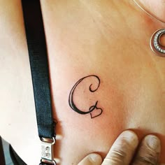 a woman's lower back tattoo with the letter c on it