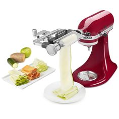 a red kitchen aid attachment on a white plate next to vegetables and sliced meats