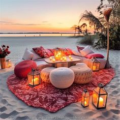 an outdoor seating area with candles and pillows on the beach