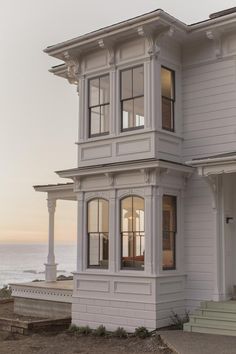 a large white house sitting next to the ocean