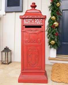 a red mailbox sitting in front of a blue door next to a christmas wreath