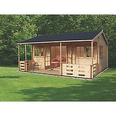 a small wooden cabin in the middle of a field with grass and trees behind it