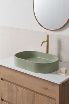 a bathroom sink with a round mirror above it and a wooden cabinet underneath the sink