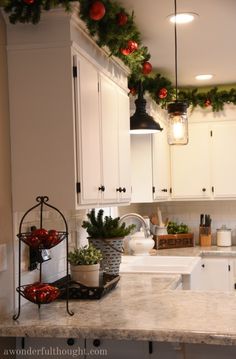 the kitchen is decorated for christmas with garland and ornaments on the counter top, along with potted plants