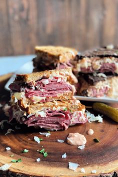 a cut in half sandwich sitting on top of a wooden cutting board next to a pickle