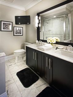 a bathroom with two sinks, a toilet and pictures on the wall above it in black and white