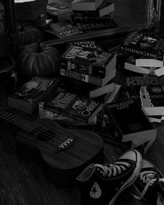 black and white photograph of guitar, books, and pumpkins on the floor in front of a mirror