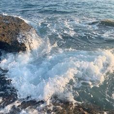 the water is splashing on the rocks by the shore