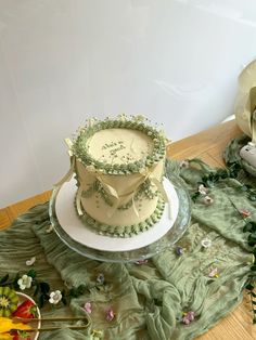 there is a wedding cake on the table with flowers and greenery around it,