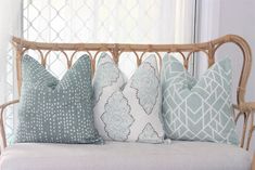 four pillows on a wicker couch in front of a window