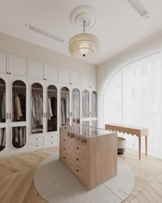 a large closet with lots of white cabinets and glass doors on the walls, along with a round rug in front of it