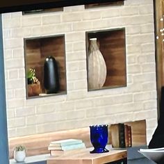 a man sitting in front of a tv with two vases on the wall behind him