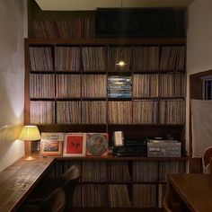 an old record player is sitting on the desk in front of a bookshelf full of records