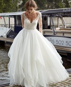 a woman in a wedding dress is standing on the dock