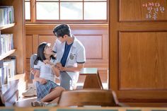 a man standing next to a woman in front of a bookshelf