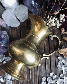 an antique brass vase surrounded by ice crystals and dried flowers on a wooden table top