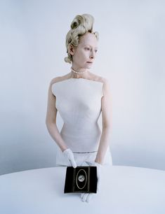 a woman in white is holding an old camera