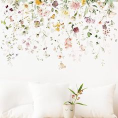 a white couch sitting next to a vase with flowers on it and a wall behind it