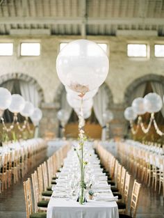 a long table is set up with clear balloons