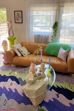 a living room filled with furniture and a glass table on top of a colorful rug