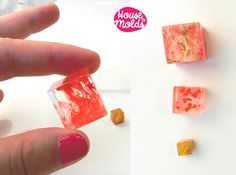 a hand is holding three small cubes that have been made out of ice and candy