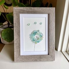 a white frame holding a blue and green flower