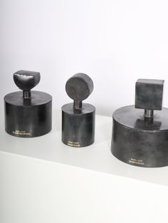 three black objects sitting on top of a white counter next to each other in front of a white wall