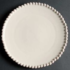 a white plate with beaded edges on a black tableclothed surface is seen in this image